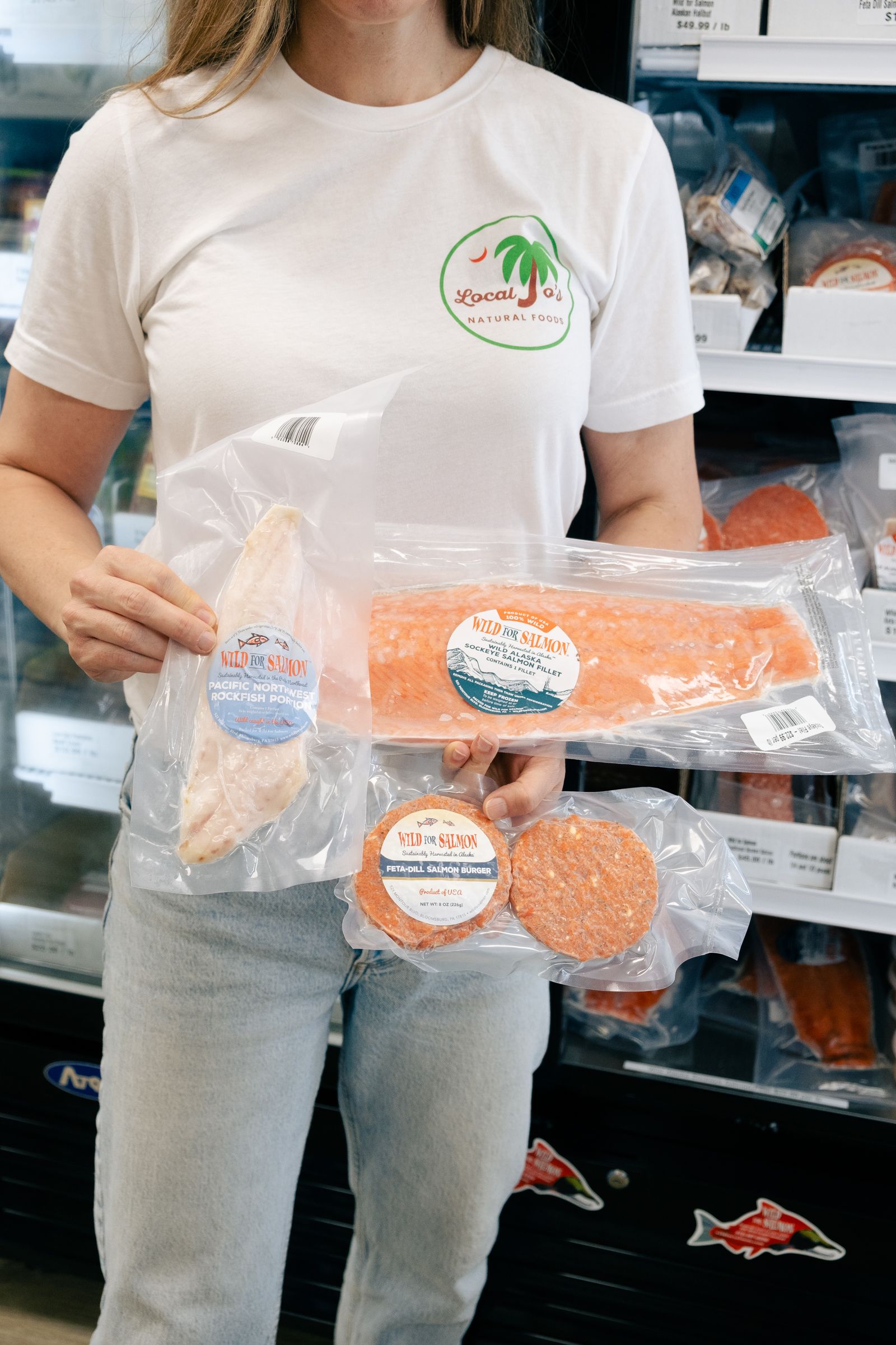 A staff member holding packaged Wild For Salmon products from the cooler